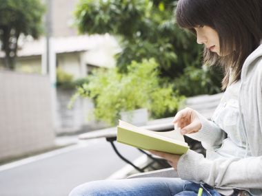 居民区户外长椅上阅读的文艺女生