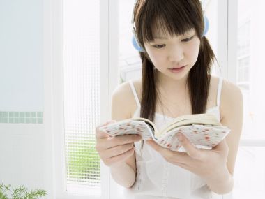 日系少女窗边戴耳机阅读的休闲放松时刻