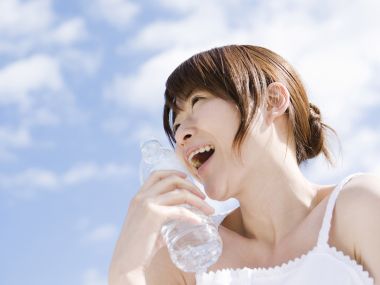 晴天户外手持矿泉水微笑的年轻女性