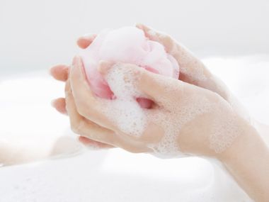 Hands Squeezing Pink Bath Sponge With Rich Foam Bath Scene