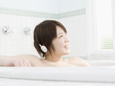 居家浴室泡澡戴耳机听音乐的清新年轻女生