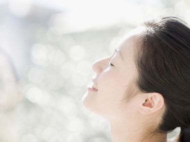 户外阳光下仰脸微笑的年轻女性治愈人像