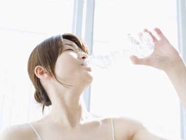 明亮窗边逆光下年轻女性饮用矿泉水 健康补水日常