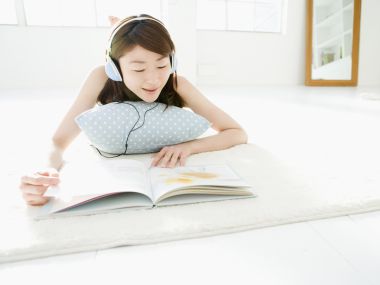 明亮居家环境中戴耳机听音乐阅读的年轻女生