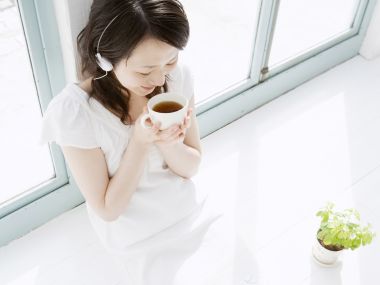 日系居家少女窗边手捧热茶戴耳机享受休闲时光