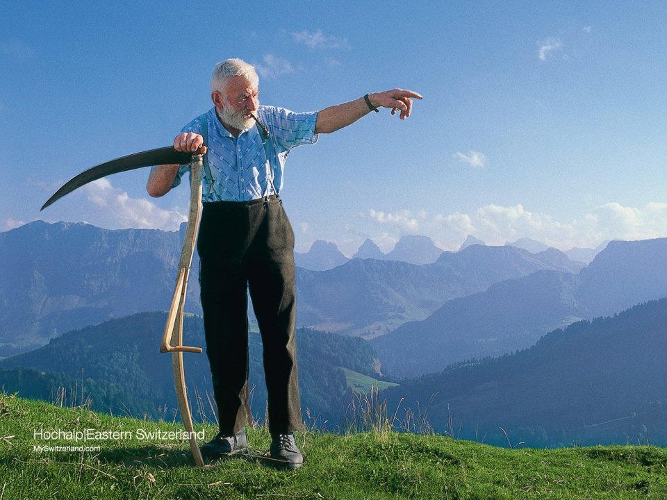 Traditional Farmer In Eastern Swiss Alps With Mountain View