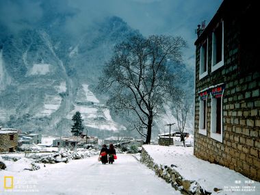 中国藏区雪景村庄 石砌建筑与雪山下的行人