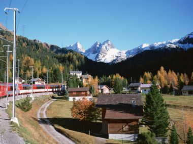 瑞士阿尔卑斯山秋景村庄与红色火车