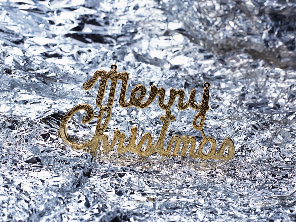 银色褶皱背景上的金色「Merry Christmas」圣诞装饰特写