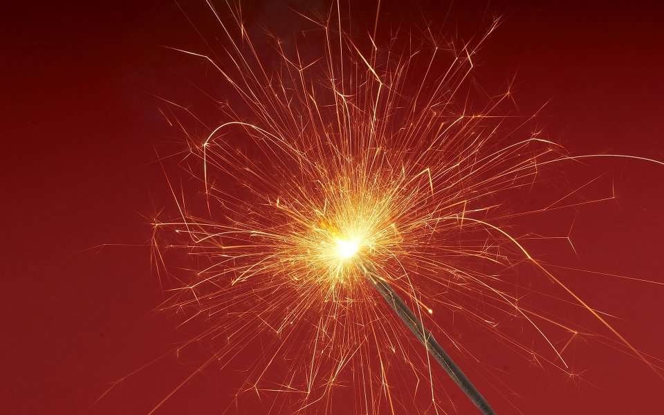 Burning Sparkler Fireworks On Red Background