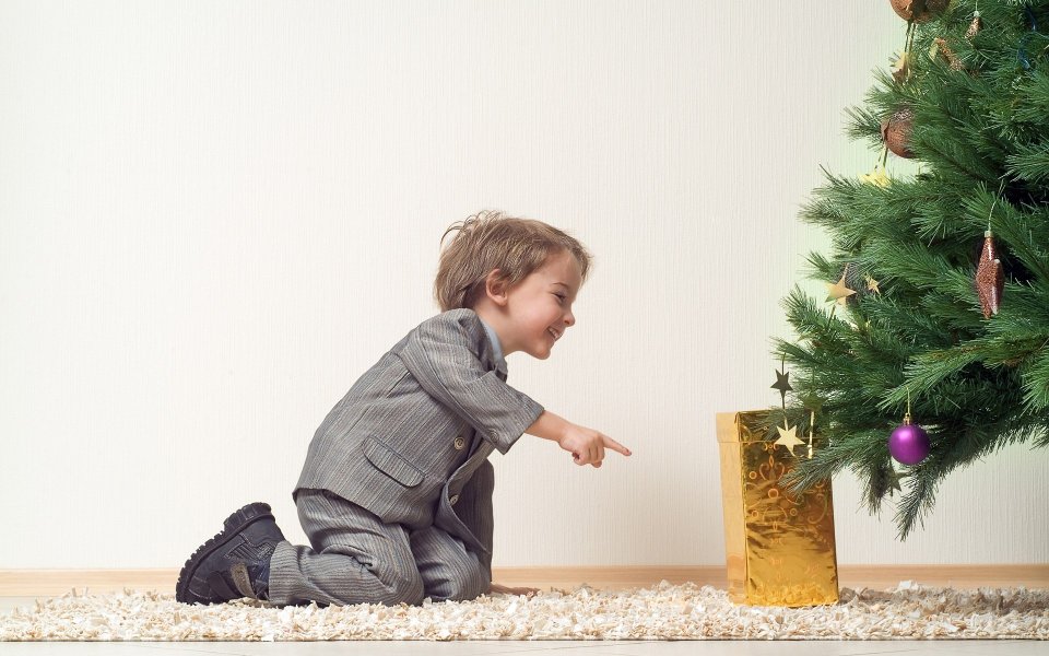 Little Boy Pointing At Christmas Gift Under Tree