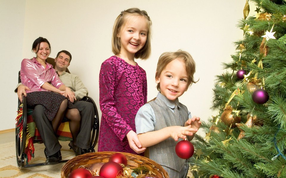 Family Decorating Christmas Tree With Mother In Wheelchair