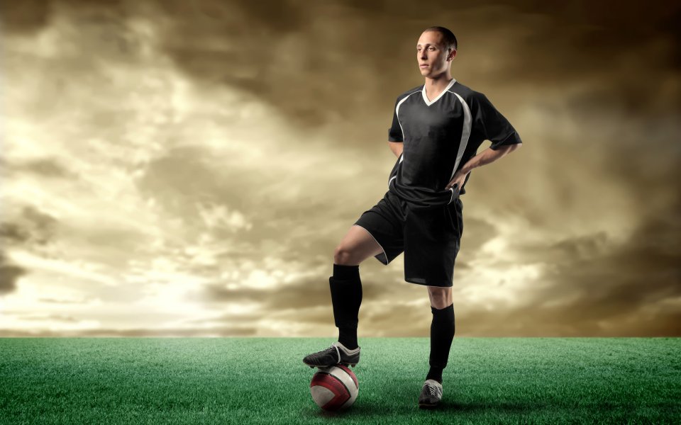 Professional Football Player Posing On Soccer Field With Ball