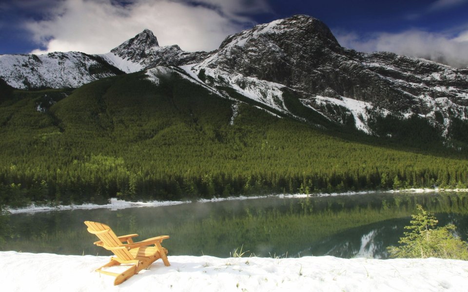 Wooden Lounge Chair Resting Under Snowy Mountain By Lake
