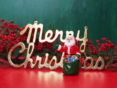 圣诞老人与金色「Merry Christmas」字样及红色浆果的节日静物特写