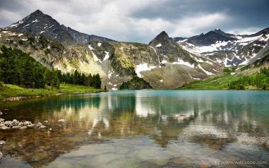 雪山针叶林环绕的碧色高山湖泊自然风光