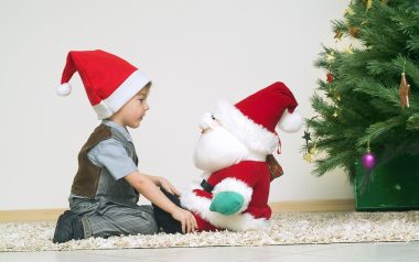 Boy Interacting With Santa Doll By Christmas Tree