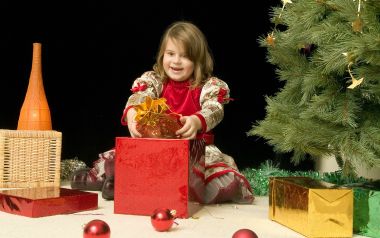 Happy Girl Opening Christmas Gift Under Tree