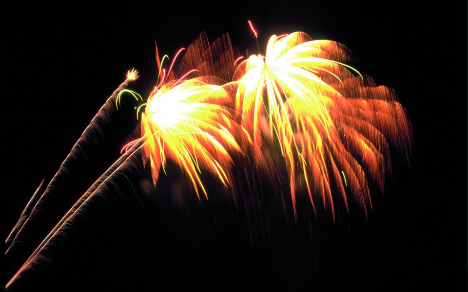 Warm Toned Festival Fireworks Blooming On Dark Night Sky