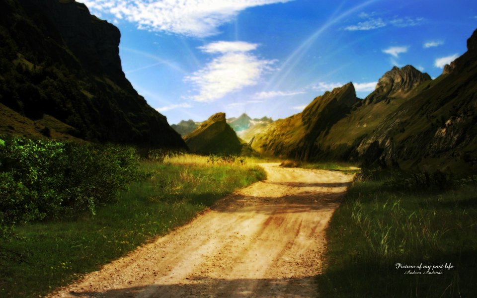 晴日蓝天下山谷间蜿蜒土路山野风光