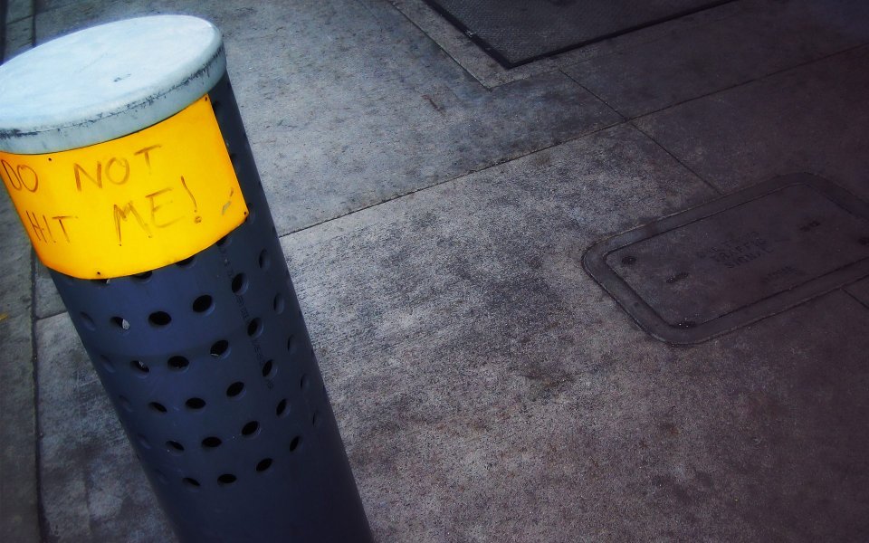 Funny Handwritten Warning Sign On Urban Sidewalk Bollard