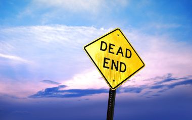 黄昏渐变天空下的黄色DEAD END死路警示路牌