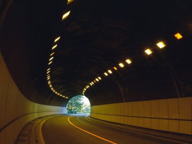 空旷弧形公路隧道 暖黄灯光通向绿意出口