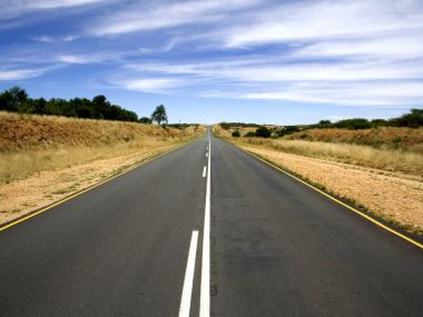 晴朗蓝天下延伸至地平线的旷野无人沥青公路