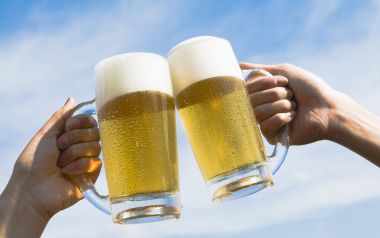HB043_350A_Two people toasting with beer against blue sky